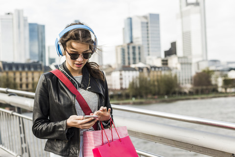 Junge Frau, die in der Stadt spazieren geht und Kopfhörer trägt, lizenzfreies Stockfoto