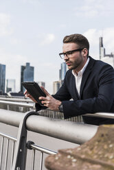 Junger Geschäftsmann mit digitalem Tablet auf einer Brücke stehend - UUF006942