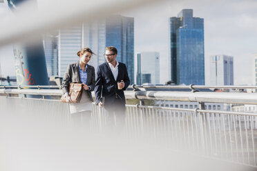 Young business couple walking on bridge, talking - UUF006947