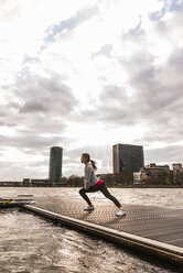 Young woman stretching at the riverseide - UUF006957