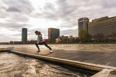 Young woman stretching at the riverseide - UUF006958