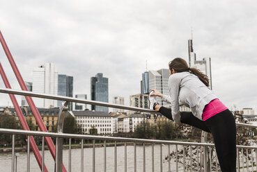 Junge Frau joggt in der Stadt, streckt das Bein - UUF006961