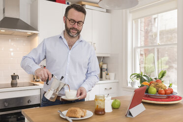 Porträt eines Mannes in der Küche, der Espresso in eine Tasse gießt - BOYF000272