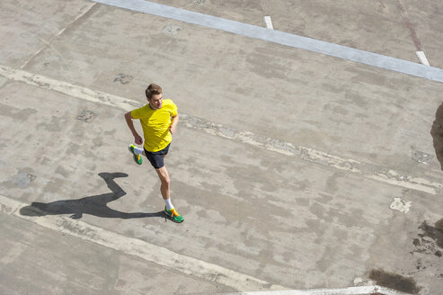 Young man jogging, concrete floor - DIGF000246