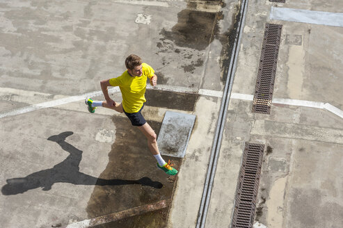 Young man jogging, concrete floor - DIGF000247