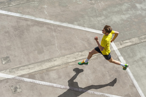 Young man jogging, concrete floor stock photo