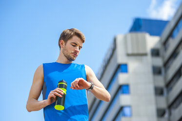 Junger sportlicher Mann mit Wasserflasche und Smartwatch - DIGF000263