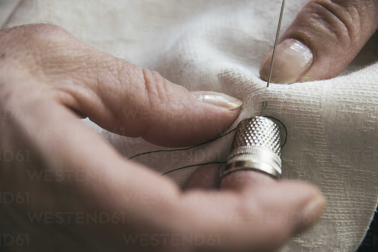 Woman with a thimble sewing stock photo