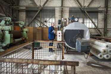 Manager in Fabrikhalle mit Blick auf die Maschine - DIGF000268