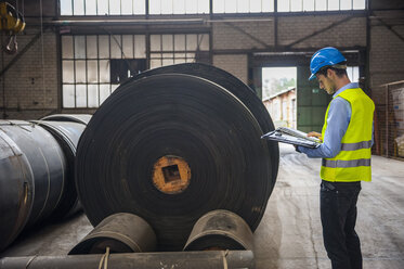 Arbeiter mit Dokumenten in einer Fabrikhalle mit Gummirollen - DIGF000270