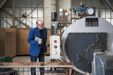 Manager in factory hall looking at machine - DIGF000281