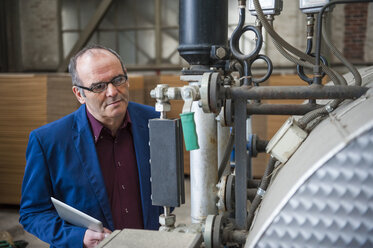 Manager in factory hall looking at machine - DIGF000282