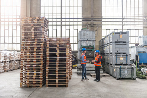 Zwei Männer unterhalten sich in einer Fabrikhalle - DIGF000296