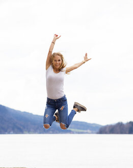 Österreich, Porträt eines glücklichen Teenagers, der in die Luft springt - WWF003939