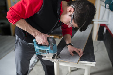 Man cutting laminate floor pieces with a jigsaw - RAEF001049