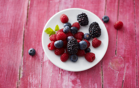 Dish of different wild berries on pink wood stock photo