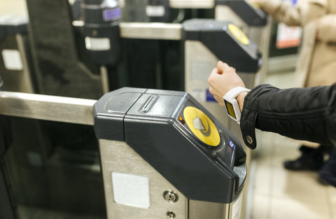 UK, London, junge Frau bezahlt Fahrkarte mit ihrer Smartwatch an einer U-Bahn-Station, lizenzfreies Stockfoto