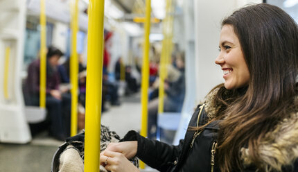 UK, London, glückliche junge Frau in einem U-Bahn-Zug - MGOF001726