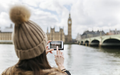 Großbritannien, London, Rückenansicht einer jungen Frau, die das Westminster-Parlament fotografiert - MGOF001731