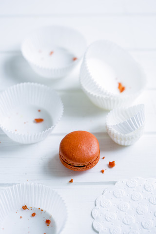 Orangefarbene Macarons und weiße Pappbecher mit Krümeln, lizenzfreies Stockfoto