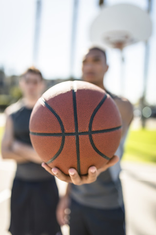 Man holding basketball on outdoor court stock photo
