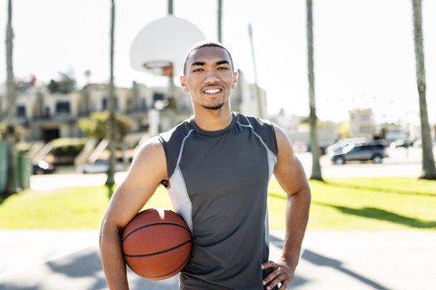 Porträt eines selbstbewussten Basketballspielers auf einem Platz im Freien, lizenzfreies Stockfoto
