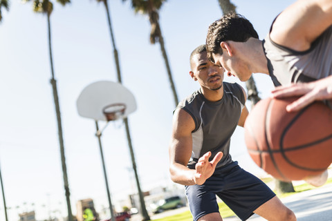 Zwei junge Männer spielen Basketball auf einem Platz im Freien, lizenzfreies Stockfoto