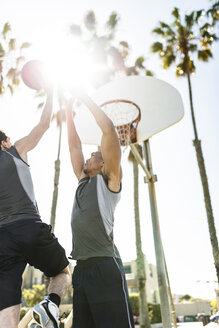Zwei junge Männer spielen Basketball auf einem Platz im Freien - LEF000106