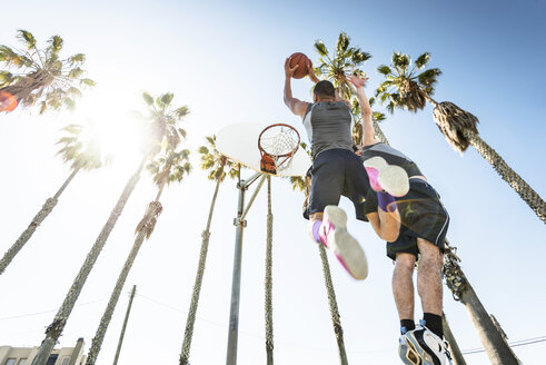Zwei junge Männer spielen Basketball auf einem Platz im Freien - LEF000108