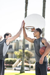 Zwei junge Männer, die sich auf einem Basketballplatz im Freien die Hände reichen - LEF000112