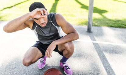 Basketball player crouching on outdoor court - LEF000119