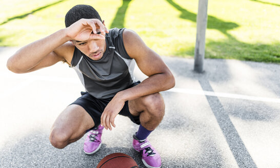 Basketballspieler hockt auf einem Platz im Freien - LEF000119