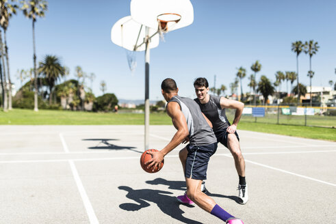 Zwei junge Männer spielen Basketball auf einem Platz im Freien - LEF000121