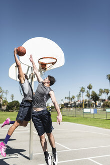 Zwei junge Männer spielen Basketball auf einem Platz im Freien - LEF000122