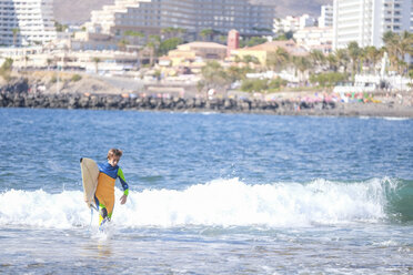 Spanien, Teneriffa, Junge mit Surfbrett im Meer - SIPF000358