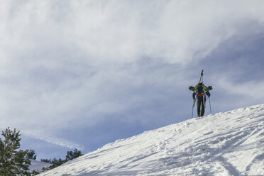 Spain, Man with skis in a backpack on top of a snowy hill, Penalara Mountain - ABZF000356