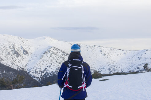 Rücken eines Skifahrers, der eine verschneite Berglandschaft beobachtet - ABZF000363
