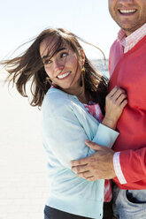 Portrait of smiling woman with blowing hair hugging by her boyfriend - VABF000448