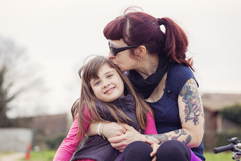 Tätowierte Frau küsst ihre lächelnde kleine Tochter - XCF000078