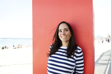 Spanien, Barcelona, Porträt einer Frau mit gestreiftem Pullover, die an einer roten Tafel lehnt - VABF000450