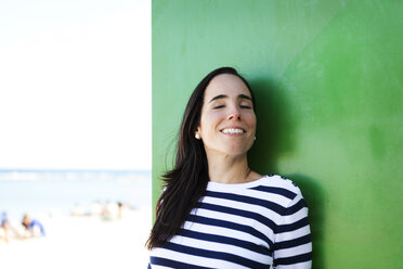 Portrait of happy woman at green wall - VABF000452