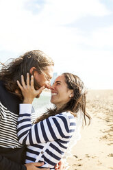 Spain, Barcelona, happy couple rubbing noses on the beach - VABF000455