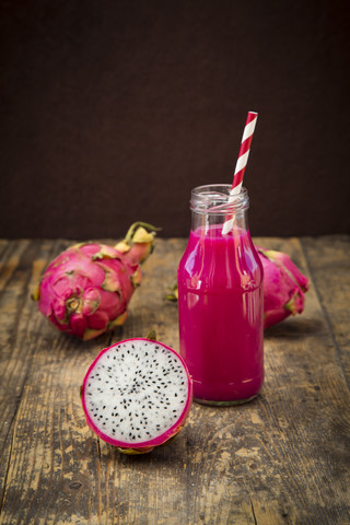 Glasflasche mit Drachenfrucht-Smoothie und eine halbe Drachenfrucht, lizenzfreies Stockfoto