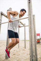 Junger Mann, der am Strand an Stangen trainiert - EBSF001329