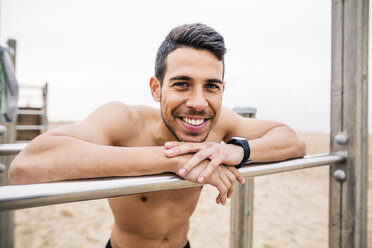 Porträt eines lächelnden Sportlers am Barren am Strand - EBSF001331