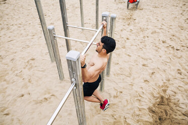 Junger Mann macht Klimmzüge am Strand - EBSF001335