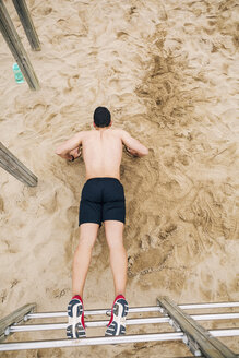 Junger Mann macht Liegestütze an der Sprossenwand am Strand - EBSF001336