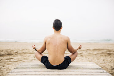 Junger Mann übt Yoga auf der Strandpromenade am Strand - EBSF001354