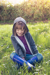 Mädchen mit Kapuzenjacke auf einer Blumenwiese sitzend - LVF004776