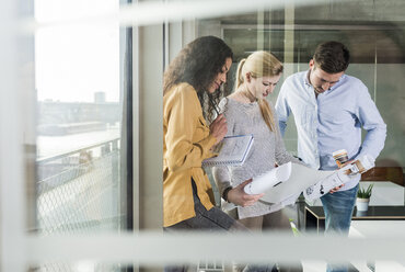 Three colleagues looking at plan in office - UUF006968